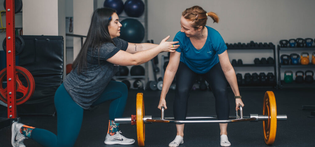 Maggie Armstrong coaching a client through a deadlift, demonstrating strength training and supportive personal coaching