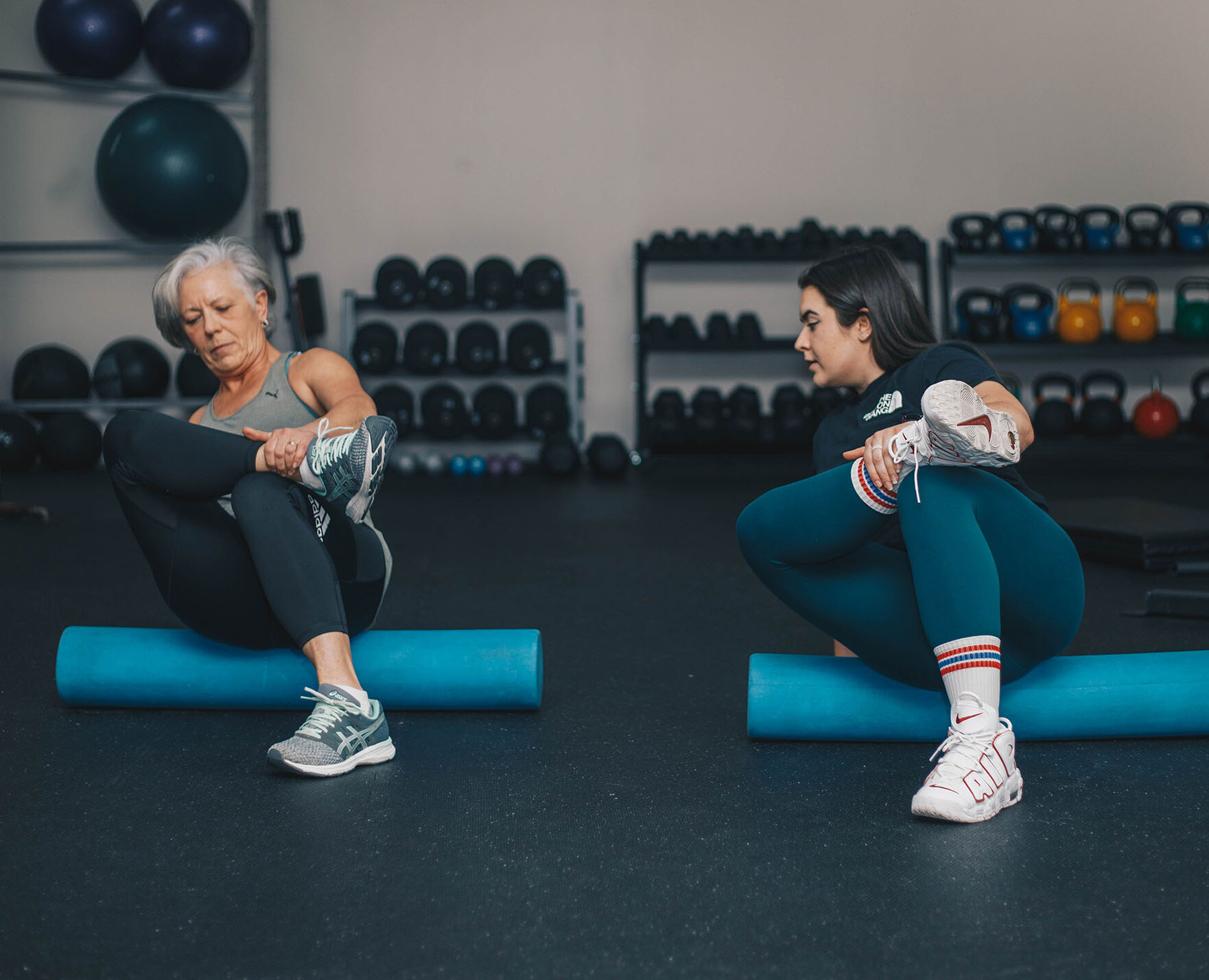 Maggie Armstrong working with a client during a personal training session using a foam roller.